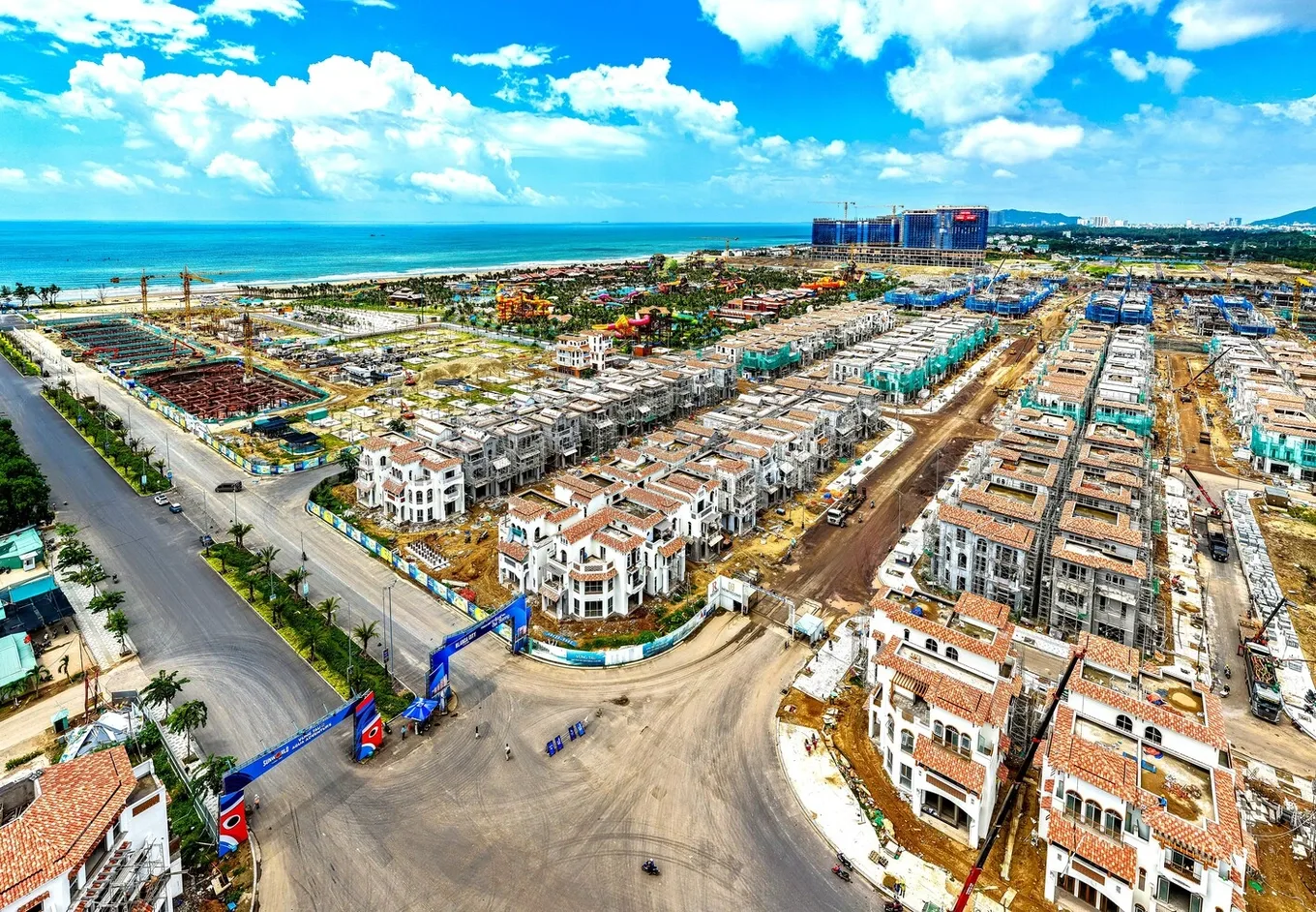 Flycam đại công trường Blanca City tháng 9/2026 — dãy biệt thự Casa lên mái, phía sau là Sun World và tháp căn hộ